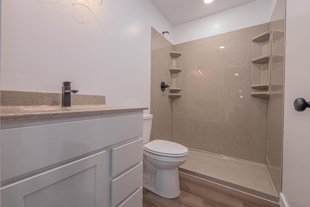 full bathroom with toilet, wood finished floors, vanity, and a walk in shower