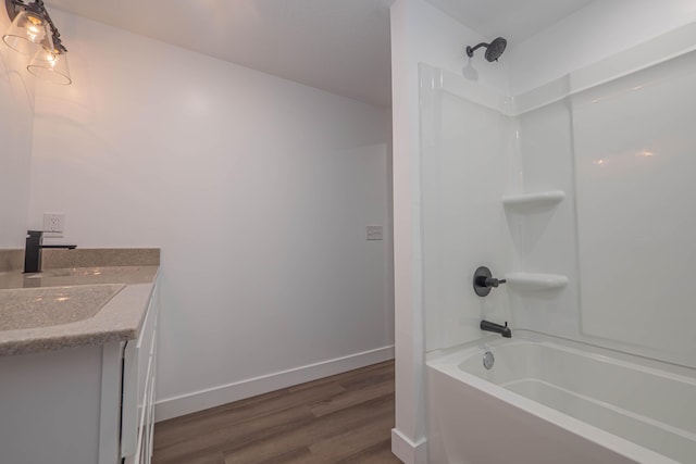 bathroom featuring baseboards, bathing tub / shower combination, wood finished floors, and vanity