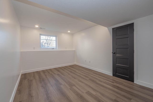 unfurnished room featuring recessed lighting, wood finished floors, visible vents, and baseboards