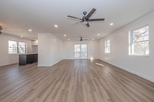 unfurnished living room with recessed lighting, light wood-type flooring, and baseboards