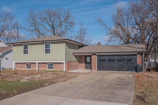 tri-level home with a garage, brick siding, driveway, and a shingled roof