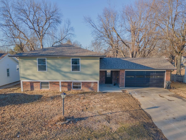 tri-level home featuring brick siding, driveway, a shingled roof, and a garage