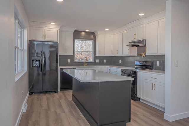 kitchen featuring a sink, black appliances, white cabinets, light countertops, and under cabinet range hood