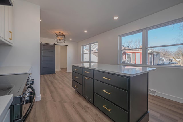 kitchen with visible vents, electric stove, white cabinetry, a barn door, and light countertops