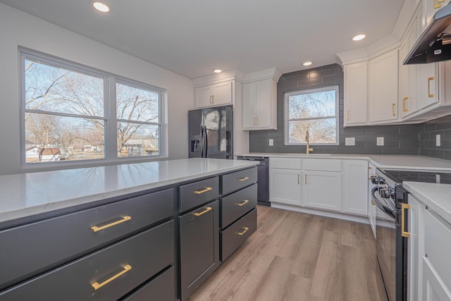 kitchen featuring under cabinet range hood, black appliances, white cabinets, and light wood finished floors