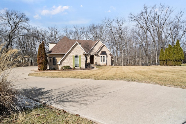 view of front of property featuring a shingled roof, driveway, and a front lawn