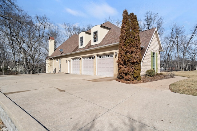 view of property exterior with a shingled roof and a detached garage