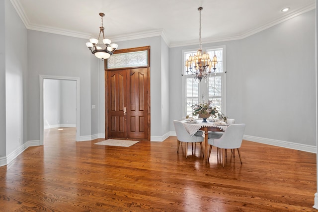 dining area with ornamental molding, wood finished floors, and a notable chandelier