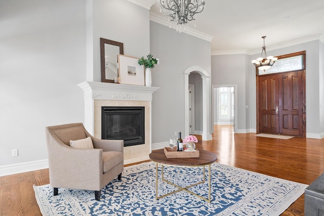 living area featuring ornamental molding, wood finished floors, baseboards, and an inviting chandelier