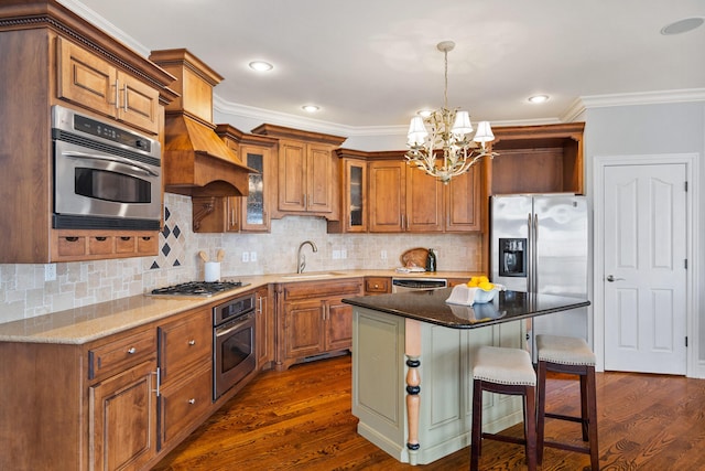 kitchen with dark wood-style floors, appliances with stainless steel finishes, a sink, and brown cabinets