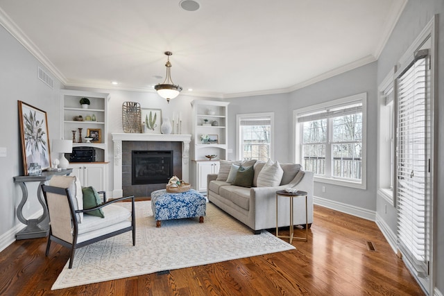 living room featuring visible vents, ornamental molding, wood finished floors, and built in shelves