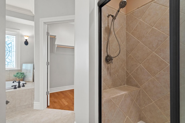 bathroom featuring a garden tub, tile patterned flooring, a tile shower, and crown molding