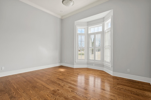 unfurnished room with crown molding, baseboards, and wood finished floors