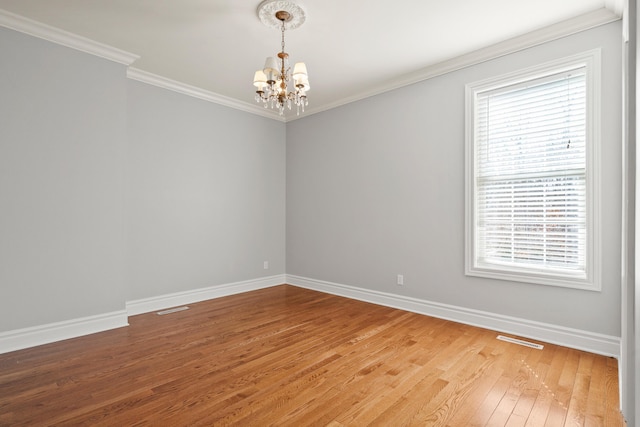 empty room with light wood finished floors, visible vents, baseboards, crown molding, and a chandelier