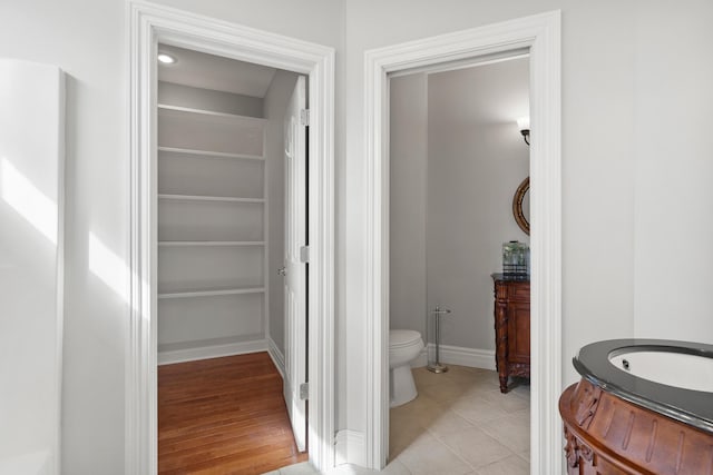 bathroom featuring baseboards, vanity, toilet, and tile patterned floors