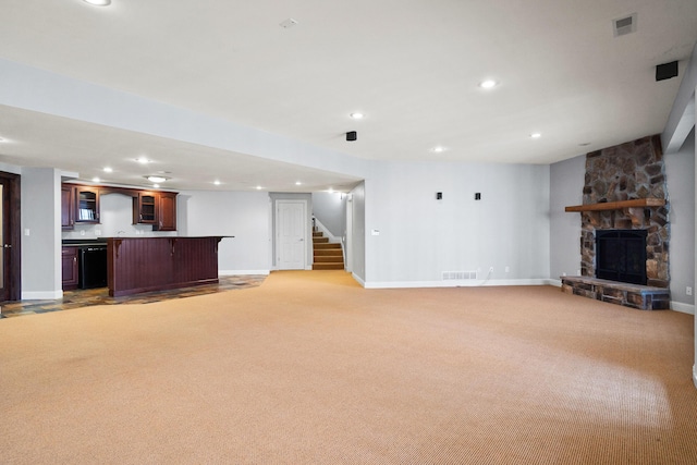 unfurnished living room featuring a stone fireplace, recessed lighting, light carpet, visible vents, and stairway