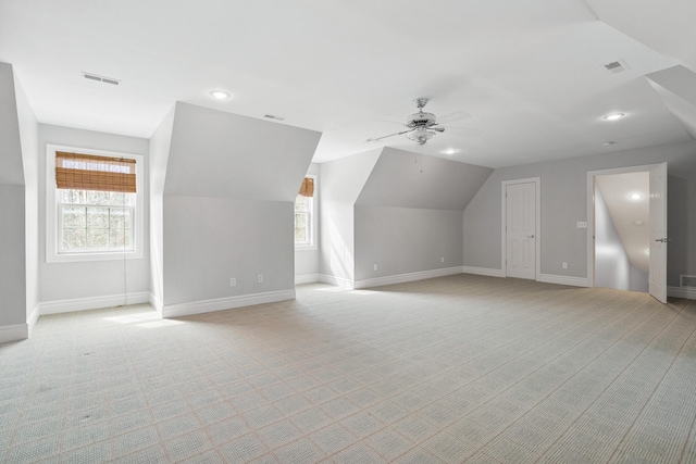 additional living space with baseboards, visible vents, and light colored carpet