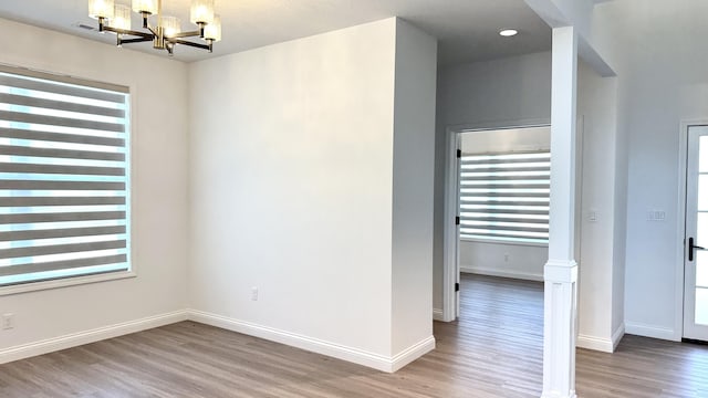 spare room with plenty of natural light, a chandelier, and hardwood / wood-style flooring