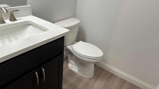 bathroom with hardwood / wood-style floors, vanity, and toilet