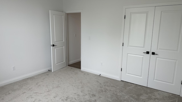 unfurnished bedroom featuring light carpet and a closet