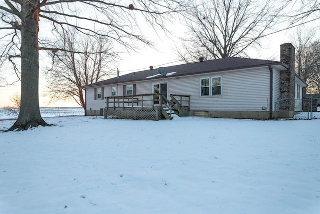 snow covered rear of property with a wooden deck