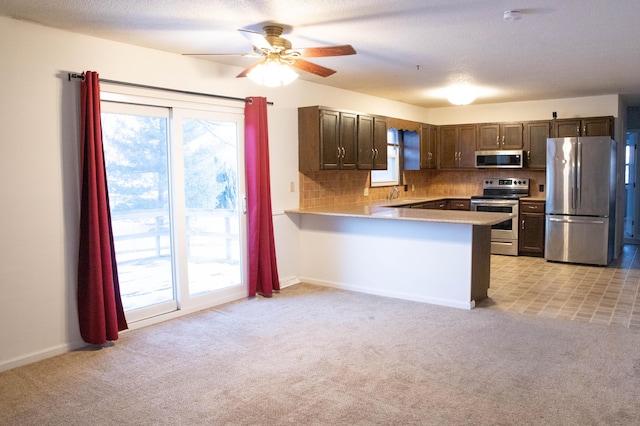 kitchen with stainless steel appliances, tasteful backsplash, kitchen peninsula, and light colored carpet