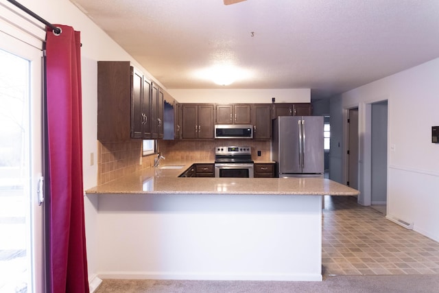 kitchen featuring stainless steel appliances, sink, tasteful backsplash, and kitchen peninsula