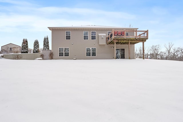 snow covered rear of property with a deck