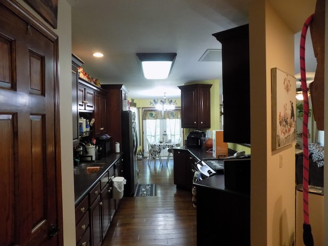 kitchen with dark brown cabinets, stainless steel fridge, sink, and dark hardwood / wood-style floors