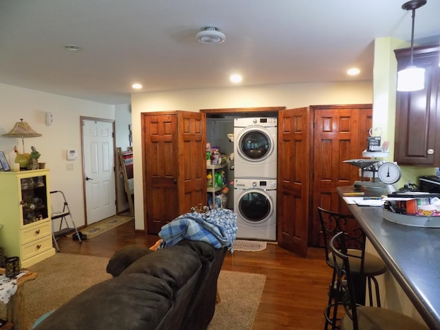 laundry area with dark hardwood / wood-style flooring and stacked washer and dryer