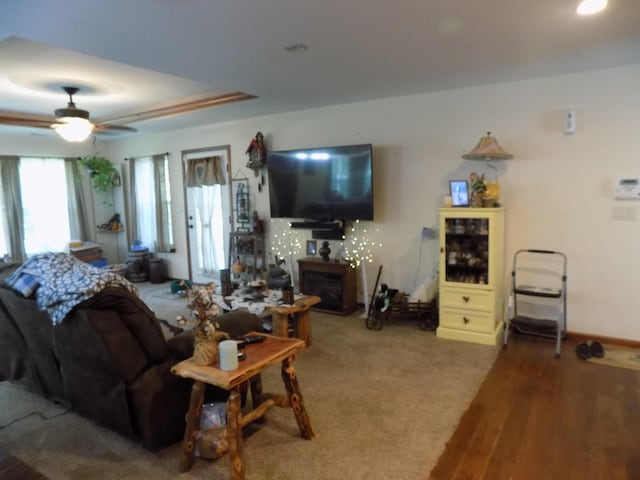 living room featuring hardwood / wood-style floors, ceiling fan, and a fireplace