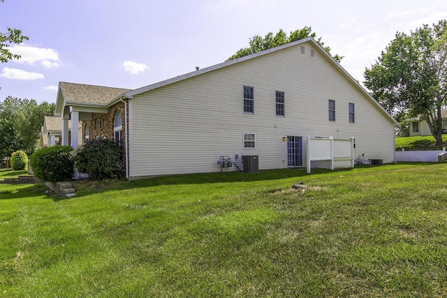 view of side of home with central AC unit and a yard