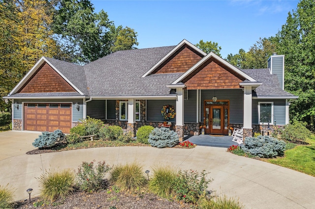 craftsman-style home featuring roof with shingles, a chimney, concrete driveway, a garage, and stone siding