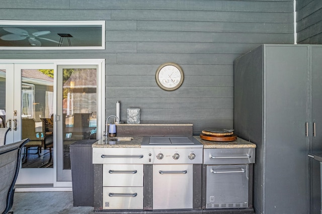 interior space with wood walls, light stone counters, sink, and french doors