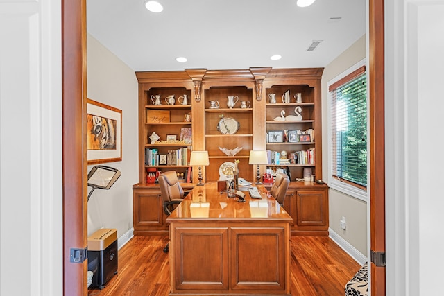 office area with built in shelves and dark hardwood / wood-style flooring