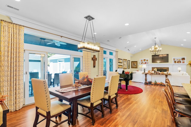 dining space featuring vaulted ceiling, crown molding, ceiling fan with notable chandelier, and hardwood / wood-style flooring