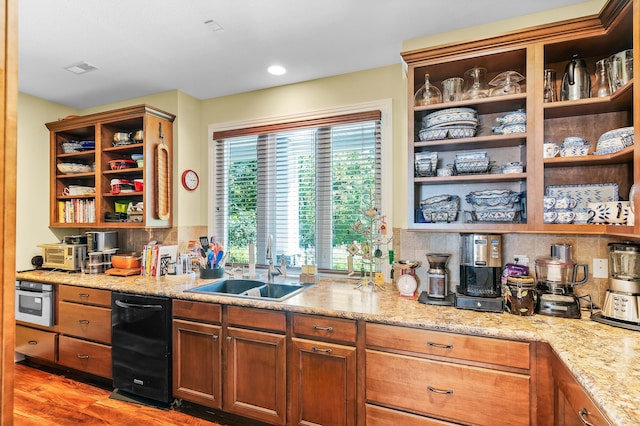 kitchen with light stone countertops, sink, hardwood / wood-style flooring, black dishwasher, and oven