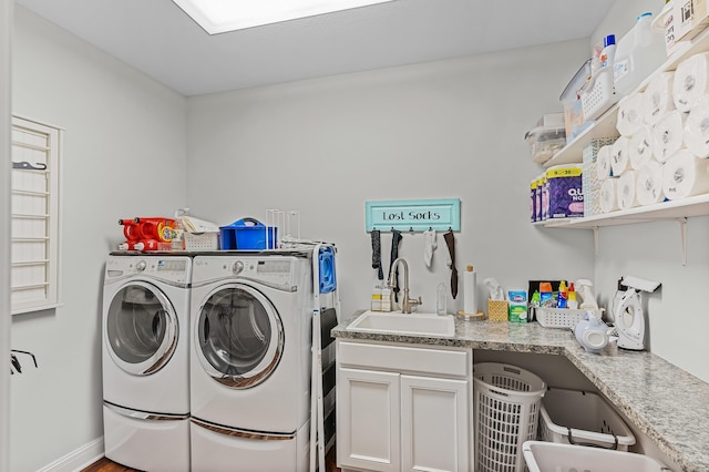 clothes washing area with washing machine and dryer, wood-type flooring, and sink