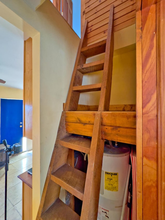 stairway featuring tile patterned floors and electric water heater