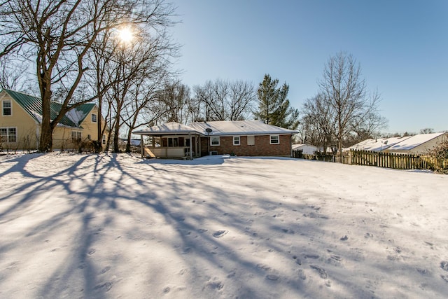 snow covered back of property with a sunroom