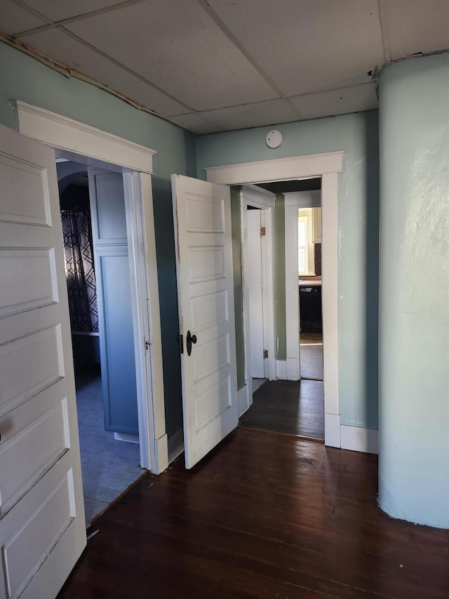 hall featuring a paneled ceiling and dark hardwood / wood-style floors