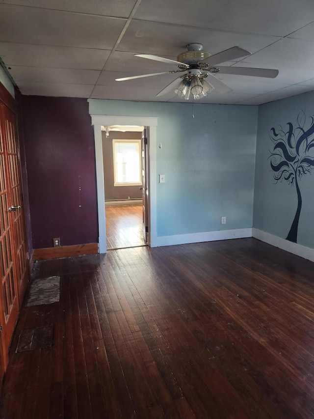 unfurnished room with ceiling fan, a drop ceiling, and dark wood-type flooring