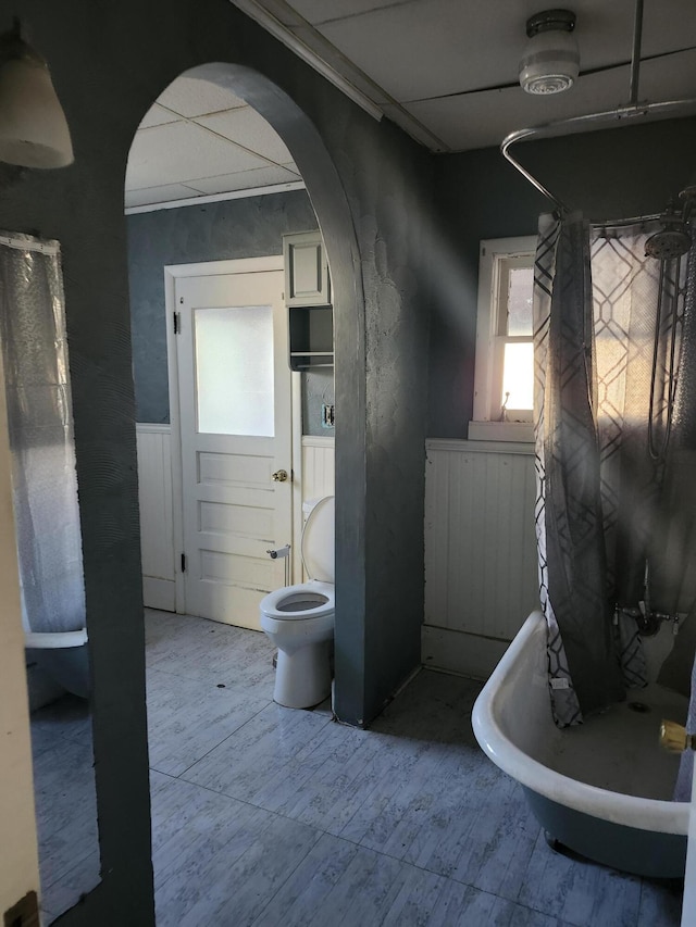 bathroom featuring toilet and a tub to relax in