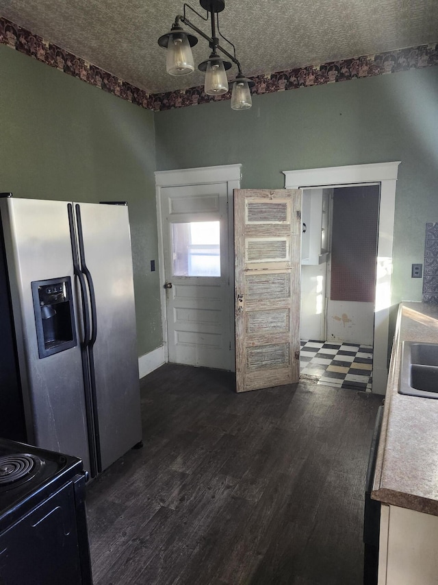 kitchen with stainless steel refrigerator with ice dispenser, dark hardwood / wood-style flooring, range with electric cooktop, sink, and hanging light fixtures