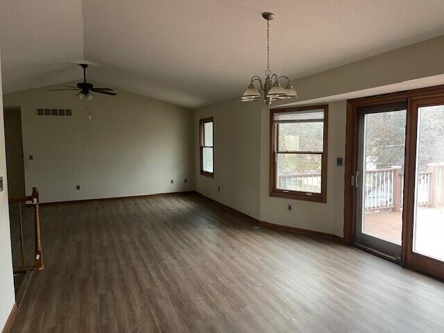 unfurnished room with lofted ceiling, ceiling fan with notable chandelier, and dark wood-type flooring