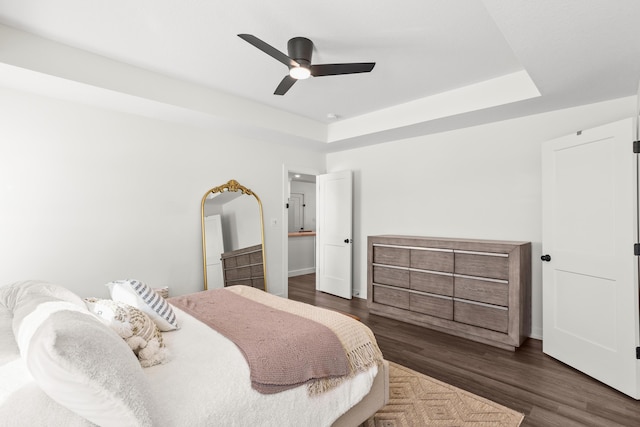 bedroom featuring dark wood-type flooring, ceiling fan, and a raised ceiling