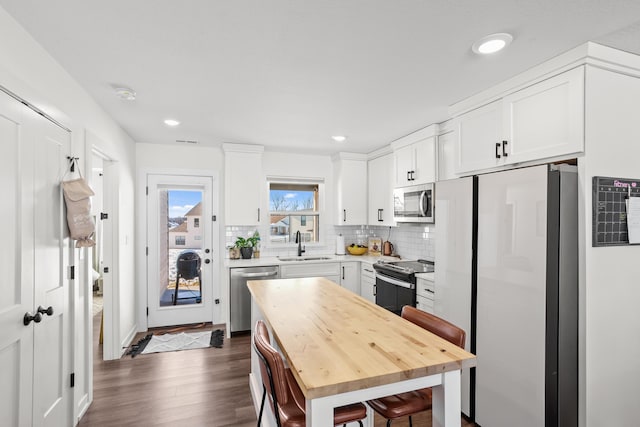 kitchen featuring tasteful backsplash, sink, dark wood-type flooring, stainless steel appliances, and white cabinets