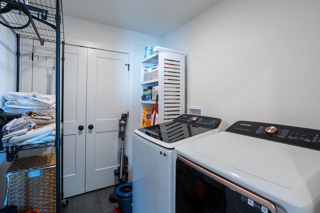 laundry area featuring washing machine and clothes dryer and dark tile patterned flooring