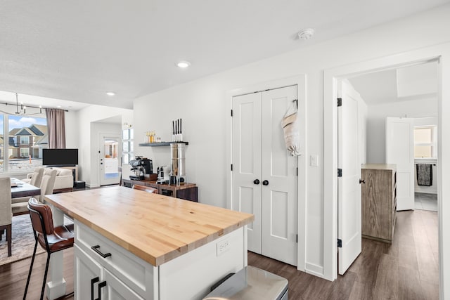 kitchen featuring an inviting chandelier, white cabinetry, butcher block countertops, dark hardwood / wood-style flooring, and a kitchen island