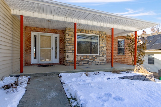 snow covered property entrance with a porch